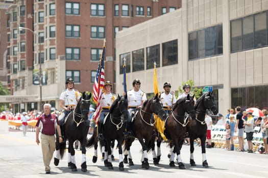 Indianapolis, Indiana, USA - May 26, 2018,  Horse riders carrying the American flag, going down the street at the Indy 500 Parade