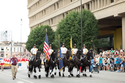 Indianapolis, Indiana, USA - May 26, 2018,  Horse riders carrying the American flag, going down the street at the Indy 500 Parade