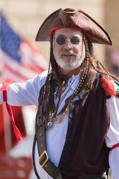 Washington, D.C., USA - April 14, 2018 A man dress as a pirate with the american flag on the background in the 2018 National Cherry Blossom Parade