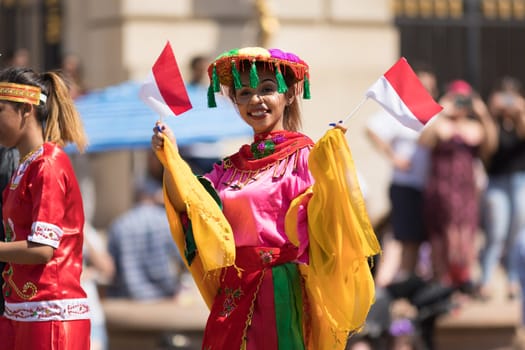 Washington, D.C., USA - April 14, 2018 People from Indonesia wearing traditional clothing walking down the street in the 2018 National Cherry Blossom Parade