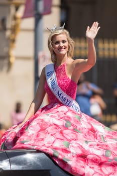 Washington, D.C., USA - April 14, 2018 Miss Maryland wearing a pink dress with pictures of cherry flowers on a car going down the road in the 2018 National Cherry Blossom Parade