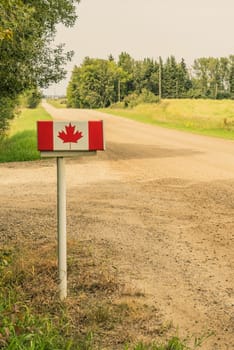 Mailbox with a Canadian flag on it along a dirt road.