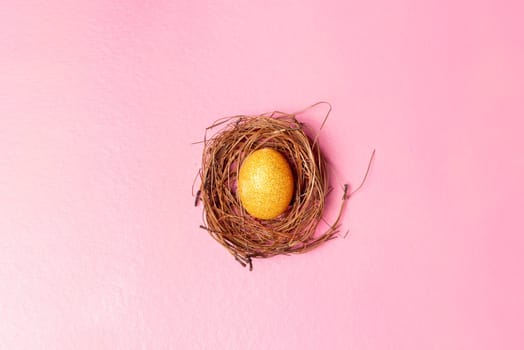 Yellow easter egg in the nest on pink color background. Happy Easter