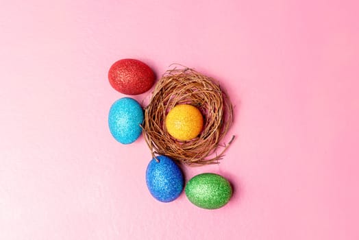 Yellow easter egg in the nest and colorful easter eggs on pink color background. Happy Easter