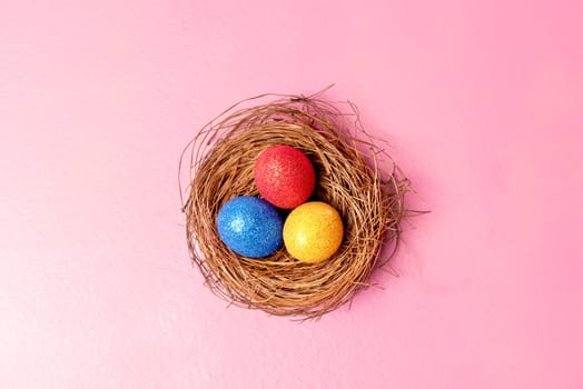 Colorful easter eggs in the nest on pink color background. Happy Easter