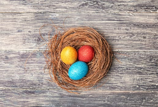 Colorful easter eggs in the nest on wooden table. Happy Easter