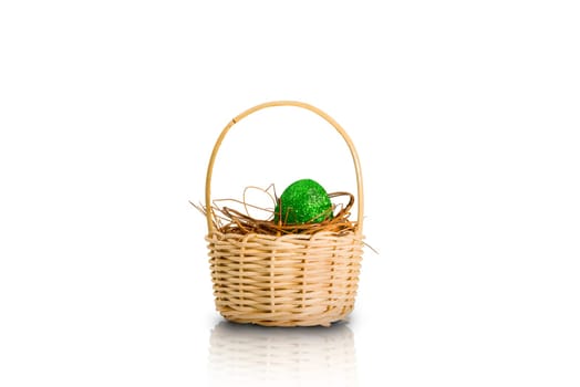 Easter egg with glitter green color in the nest on wooden basket isolated over white background