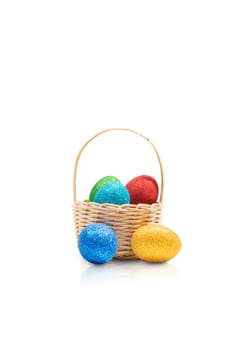Colorful easter eggs with glitter on wooden basket isolated over white background. Happy Easter