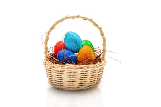 Colorful easter eggs with glitter in the nest on wooden basket isolated over white background. Happy Easter