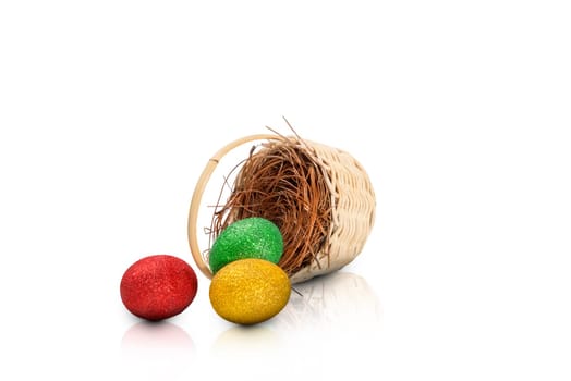 Colorful easter eggs spilled from nest on wooden basket isolated over white background. Happy Easter