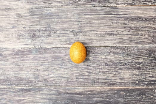 Easter egg with glitter yellow color on wooden table. Happy Easter