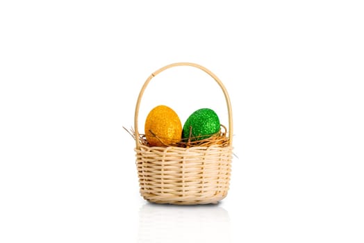 Easter egg with glitter green and yellow color in the nest on wooden basket isolated over white background. Happy Easter