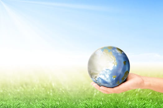 Human hand holding earth planet with green grass over blue sky background. Earth day concept
