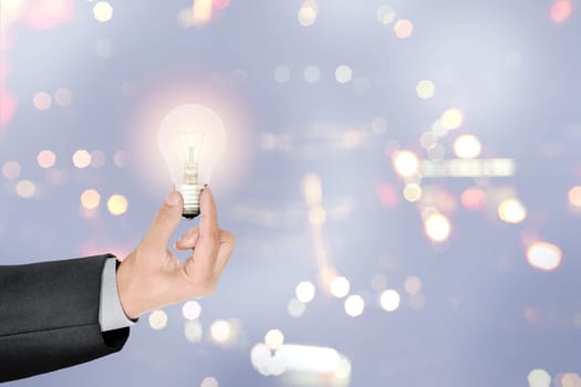 Businessman hands holding bright light bulb as a symbol of creative idea over blurred light background