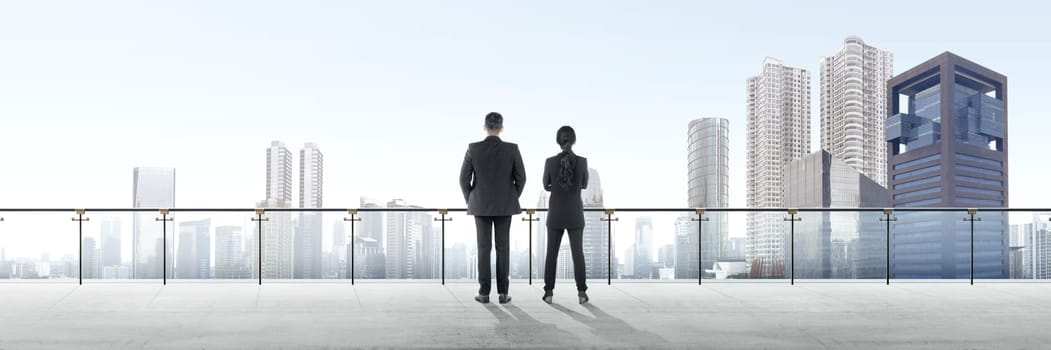 Rear view of two asian business people standing on modern terrace and looking at view on the city