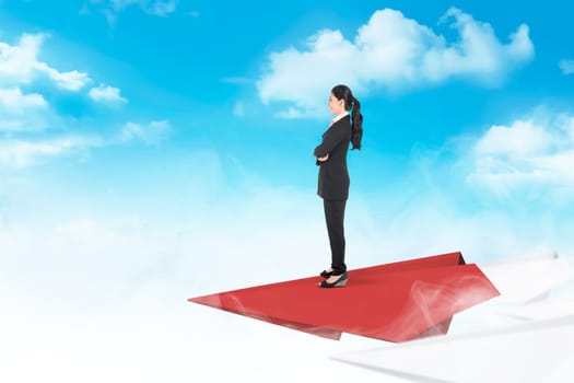 Beautiful asian business woman standing on paper plane flying with cloud and blue sky background. Business concept