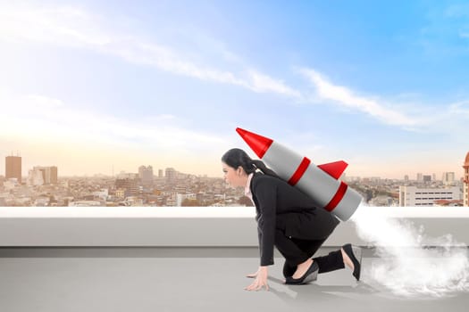 Excited asian business woman on the rooftop with rocket ready to fly. Business concept