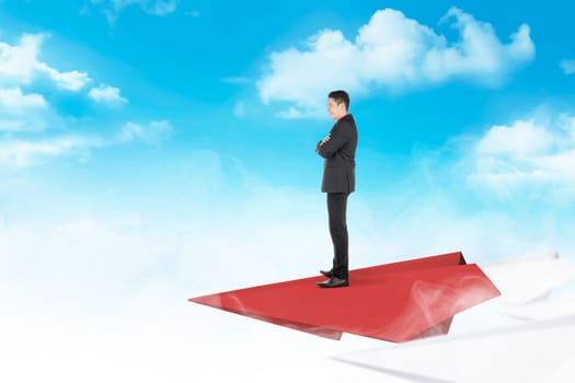Handsome asian businessman standing on paper plane flying with cloud and blue sky background. Business concept