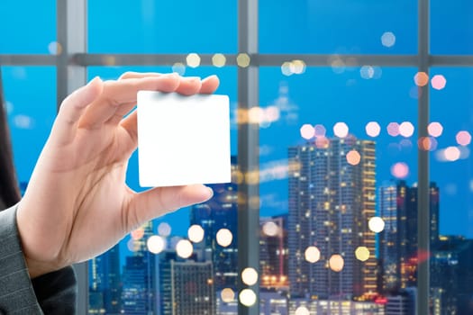 Business woman hand showing white blank card on the office with city at night background. White blank card for copyspace