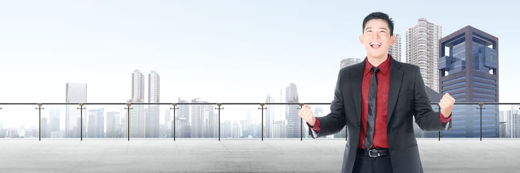 Successful asian businessman standing on modern terrace with cityscapes background
