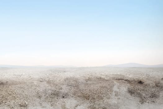 Soil drought on the field with smoke over blue sky background
