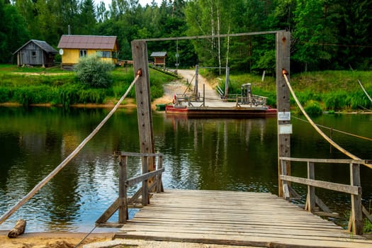 Ligatne ferry crossing on the bank of river Gauja. Ferry across river in Latvia. The ferry over Gauja river is the only crossing of this type in the Baltic States. Ferry is made of two boats fastened together on which there is a plank layer...