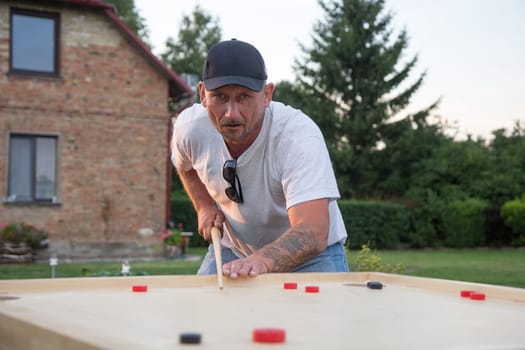 Man playing Novuss in outdoors. Novuss is a national sport in Latvia similar to pocket billiards or pool.