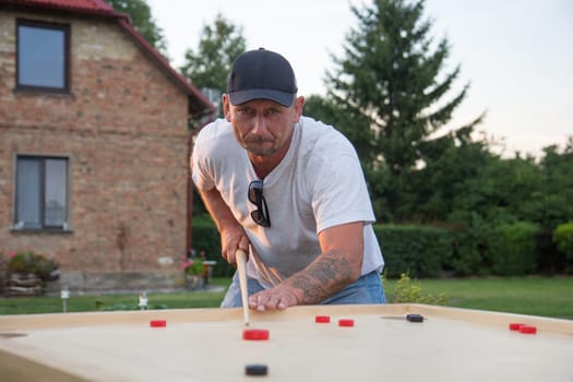 Man playing Novuss in outdoors. Novuss is a national sport in Latvia similar to pocket billiards or pool.