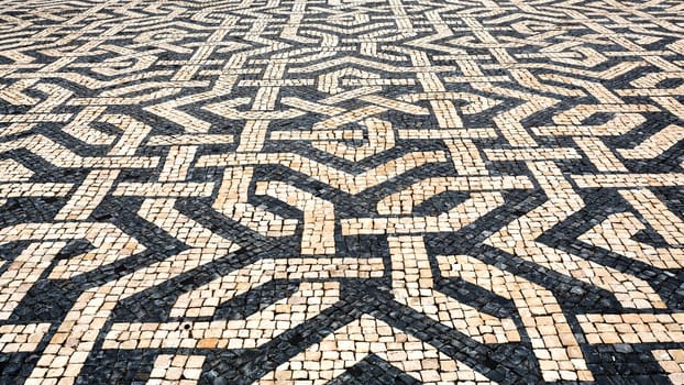 Typical Portuguese cobblestone pavement creating balck and white patterns using basalt and limestone cobbles, in Lisbon, Portugal