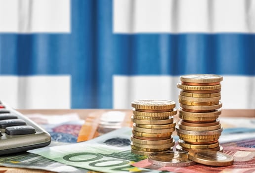 Euro banknotes and coins in front of the national flag of Finland
