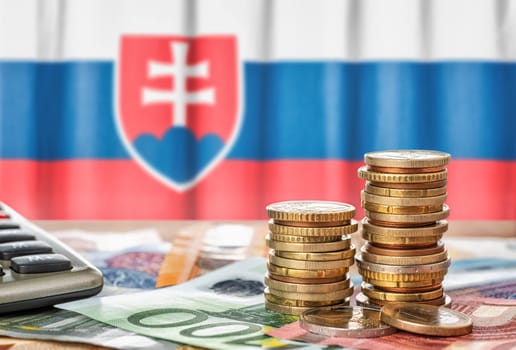 Euro banknotes and coins in front of the national flag of Slovakia