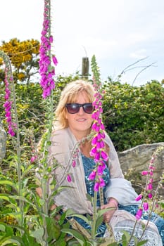 beautiful middle aged woman among wild fox gloves in the irish countryside