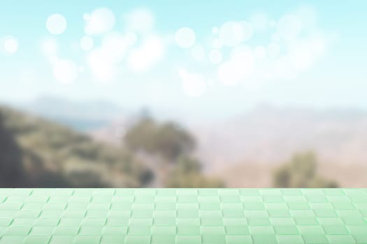 Empty table top summer background. Empty wooden deck table with bright green tablecloth over abstract blurred natural summer or spring landscape. Template for product display montage. Space.