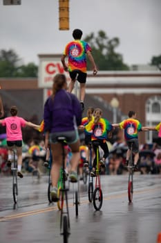 Peru, Indiana, USA - July 21, 2018 Men and women riding unicycles under the rain at the Circus City Festival Parade