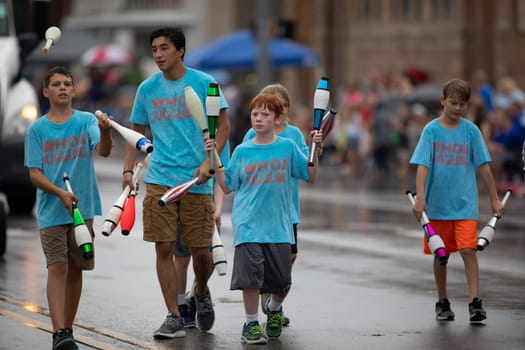 Peru, Indiana, USA - July 21, 2018 Young men wearing shirts that say Whoa Juggling, juggling bowling pins at the Circus City Festival Parade