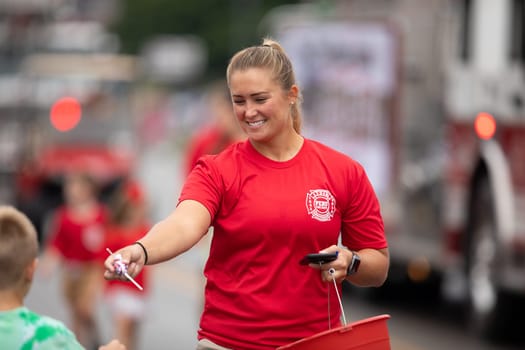 Peru, Indiana, USA - July 21, 2018  Woman wearing a Peru Fire Dept shirt giving away candy to children at the Circus City Festival Parade