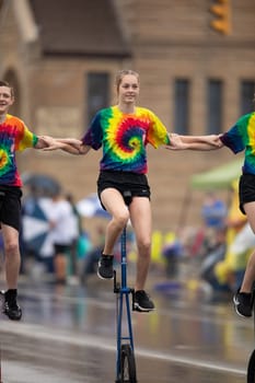 Peru, Indiana, USA - July 21, 2018 Men and women riding unicycles under the rain at the Circus City Festival Parade
