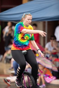 Peru, Indiana, USA - July 21, 2018 Men and women riding unicycles under the rain at the Circus City Festival Parade