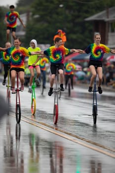 Peru, Indiana, USA - July 21, 2018 Men and women riding unicycles under the rain at the Circus City Festival Parade