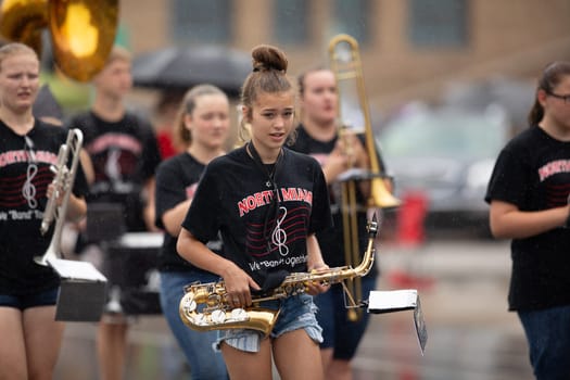 Peru, Indiana, USA - July 21, 2018 Under heavy rain Members of the North Miami High school marching band perform at the Circus City Festival Parade
