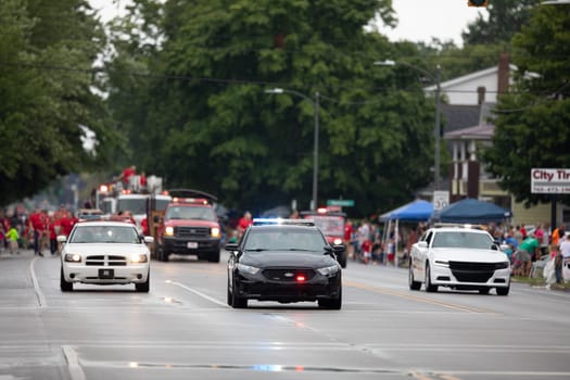 Peru, Indiana, USA - July 21, 2018 Police Officers and fire fighters going down the road at the Circus City Festival Parade