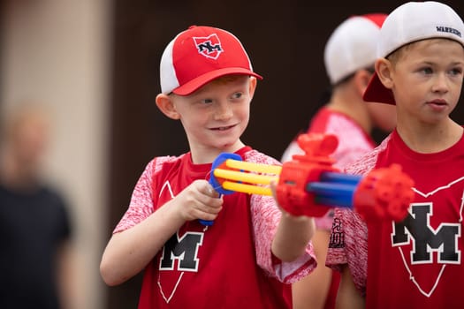 Peru, Indiana, USA - July 21, 2018 Children playing with a toy gun aiming it at the spectators at the Circus City Festival Parade