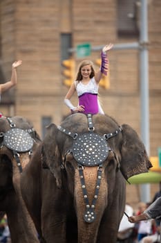 Peru, Indiana, USA - July 21, 2018 Young women riding elephants down the road at the Circus City Festival Parade