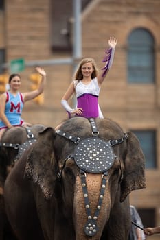 Peru, Indiana, USA - July 21, 2018 Young women riding elephants down the road at the Circus City Festival Parade