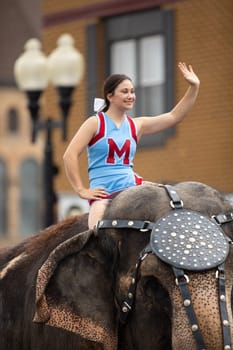 Peru, Indiana, USA - July 21, 2018 Young women riding elephants down the road at the Circus City Festival Parade