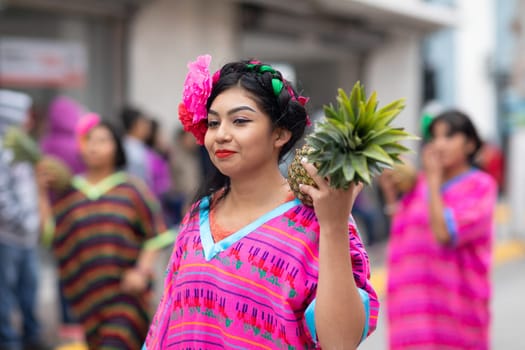 Matamoros, Tamaulipas, Mexico - November 20, 2018: The November 20 Parade, Young woman wearing traditional mexican clothing carrying a pineapple down the street