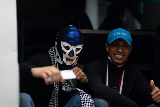 Matamoros, Tamaulipas, Mexico - November 20, 2018: The November 20 Parade, Two young men, one wearing a luchador mask pose for the camera while holding a phone