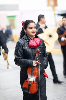 Matamoros, Tamaulipas, Mexico - November 20, 2018: The November 20 Parade, Young woman dress up as a mariachi carrying a violin, walking down the street at the parade