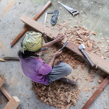 Unrecognizable carpenter working with manual tools in traditional carpentry shop in developing country. Heavy labour intensive manual work.