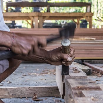 Close up of warn hands of carpenter working with manual tools in traditional carpentry shop in a third world country. Heavy labour intensive manual work.